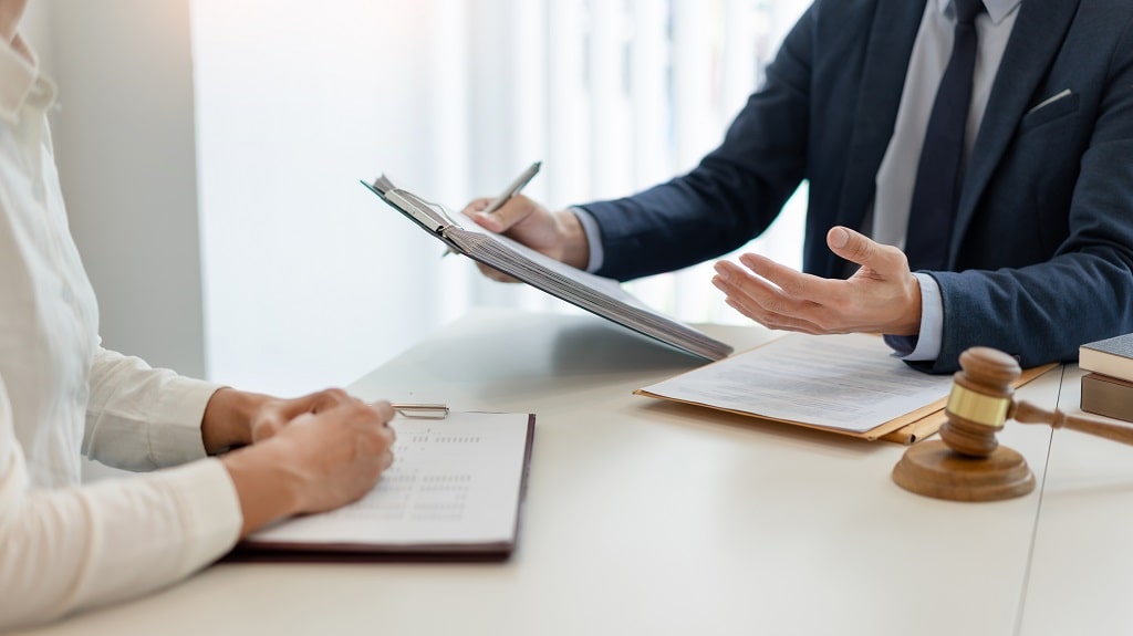 Lawyer discussing documents with client at desk with gavel