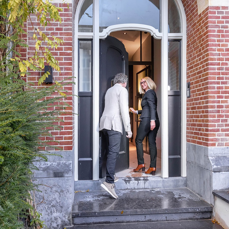 Estate agent welcoming client at front door of townhouse